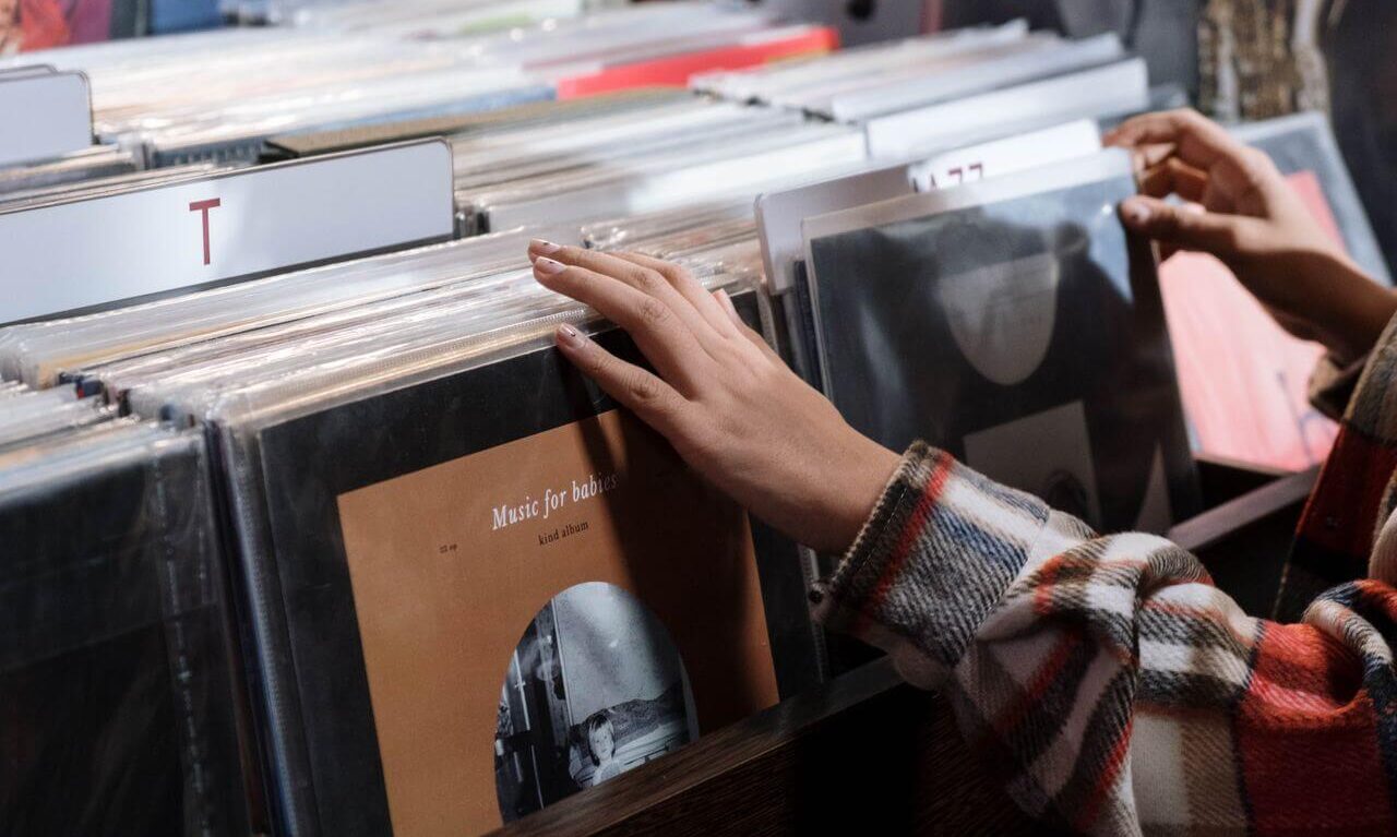 Hands flipping through vinyl records in a record store, illustrating the 2026 vinyl revival