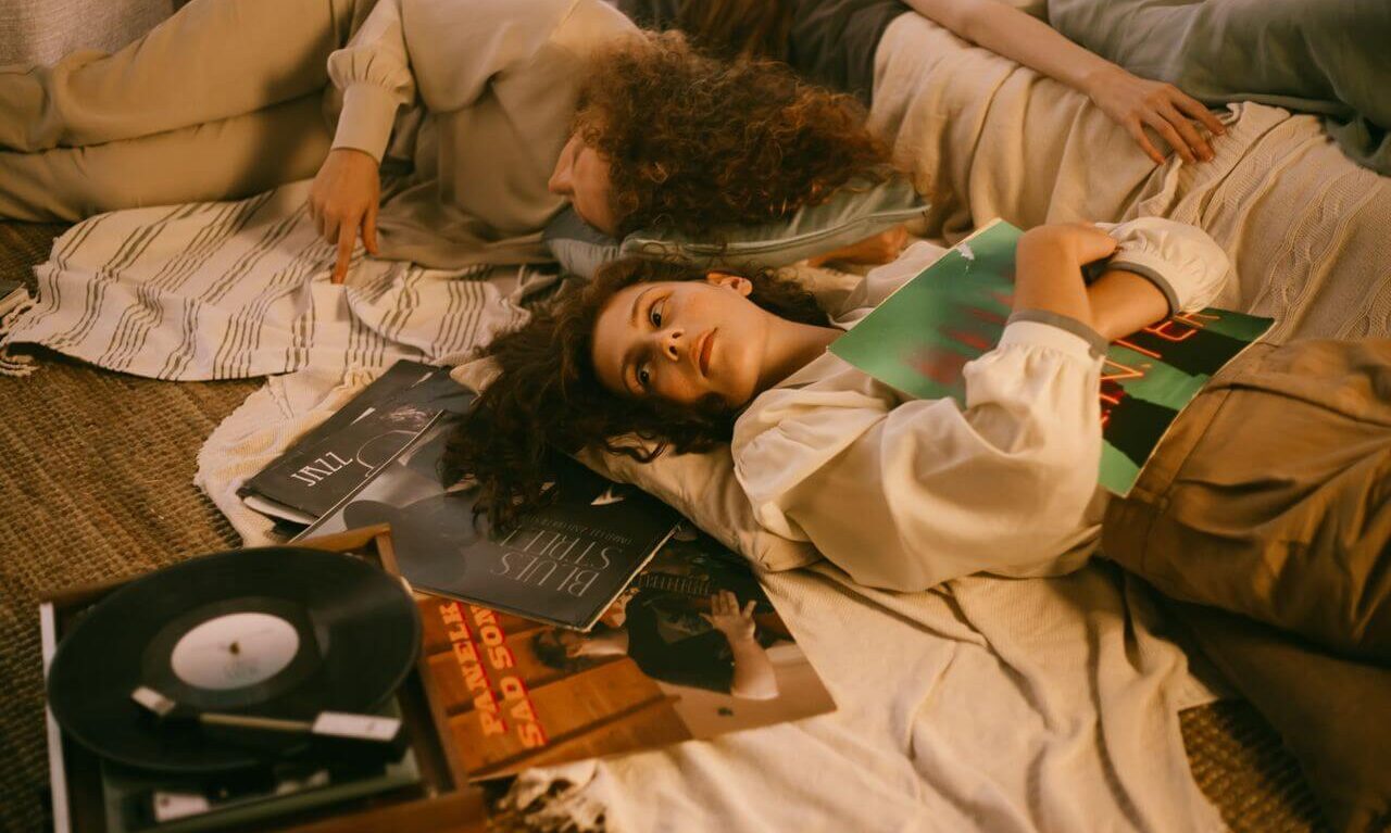 Gen Z listener discovering music through vinyl records and radio instead of a phone algorithm in 2026